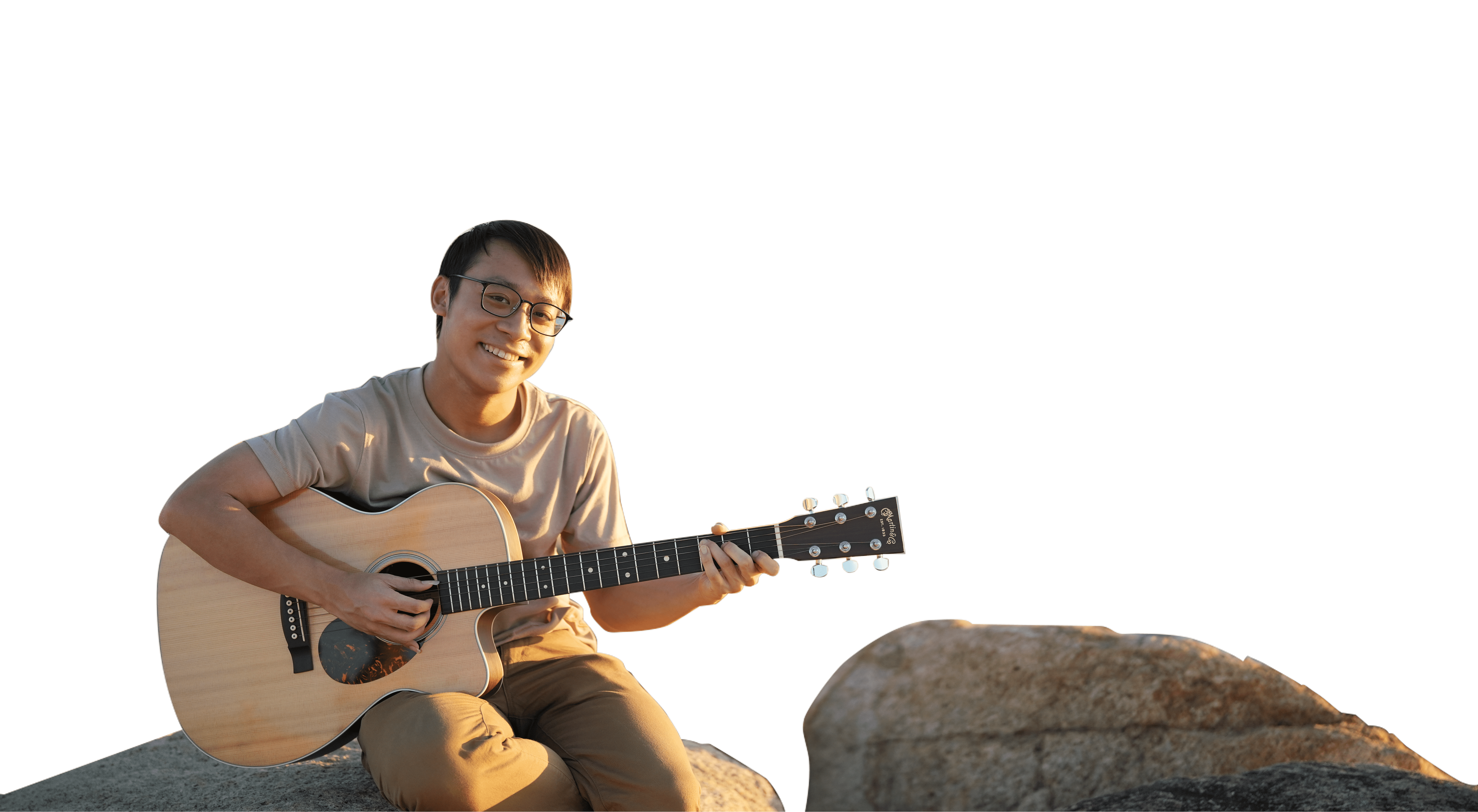 A musician playing the guitar on a rocky beach